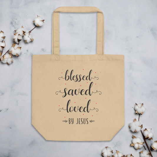 Natural-colored organic cotton tote bag with “Blessed Saved Loved by Jesus” quote in script font surrounded by sweet floral