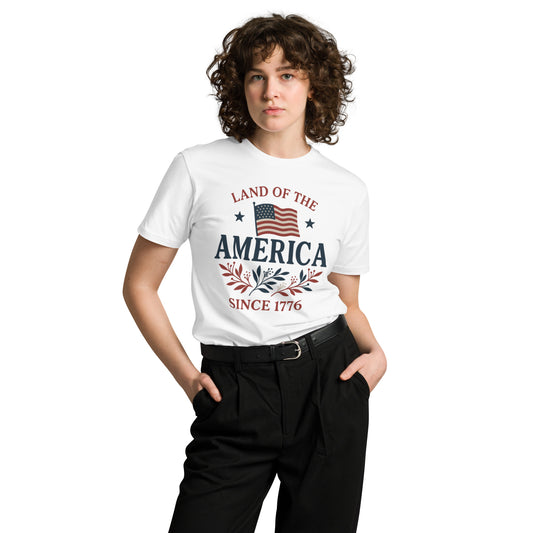 Model wearing a white t-shirt with “Land of the America Since 1776” text, an American flag, and patriotic floral graphics – Independence Day clothing
