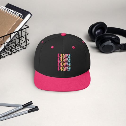 Black structured Christian snapback cap with floral “PRAY ON IT” design and flat brim