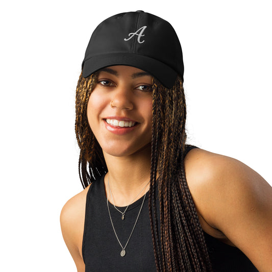 Woman wearing a black performance cap with an embroidered “A” and curved visor, designed for everyday and workout wear
